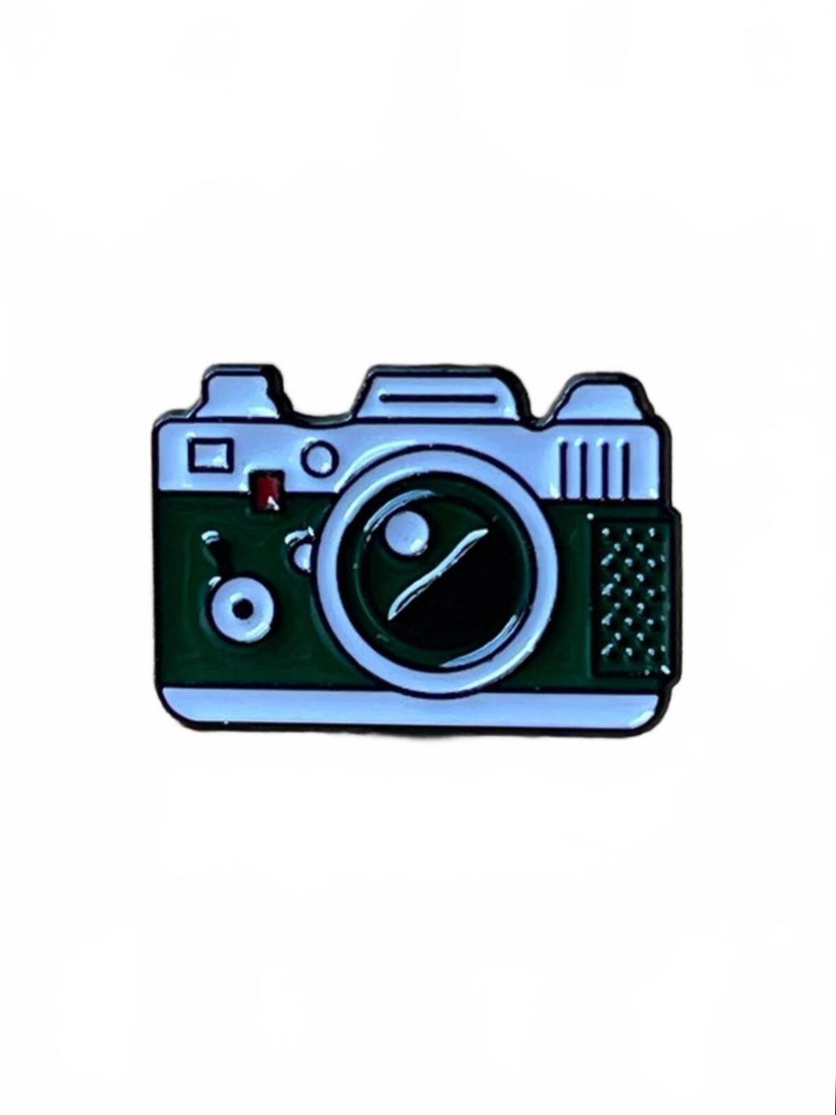 Green and white camera enamel pin on a white background