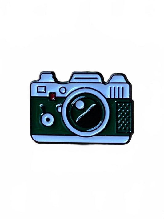 Green and white camera enamel pin on a white background