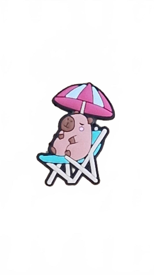 Cute capybara relaxing on green deck chair with white and pink umbrella shoe charm