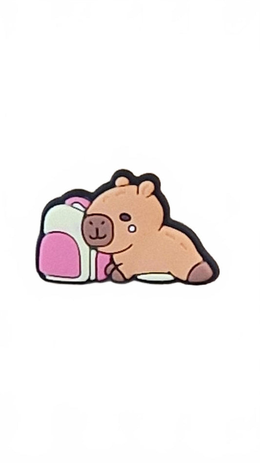 Cute capybara lying next to a white and pink backpack on a white background
