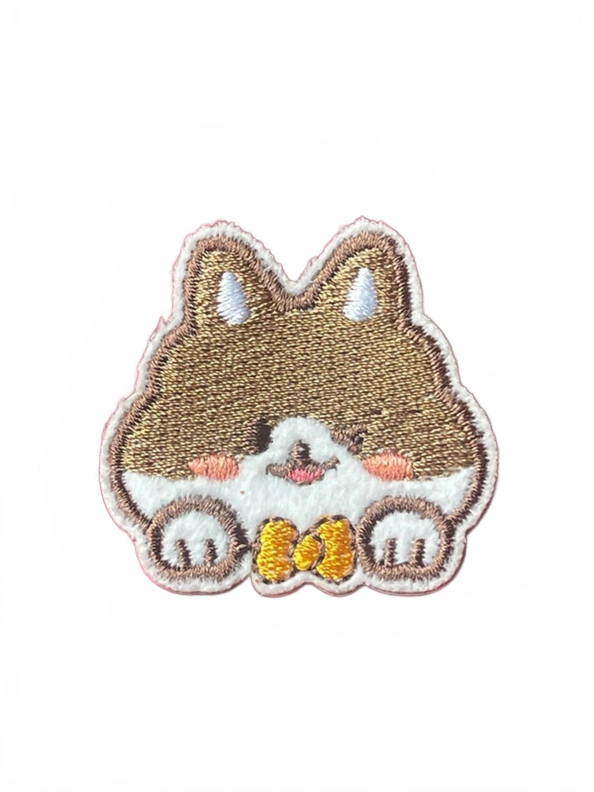 Cute embroidered patch of a cartoon corgi dog face with paws and a yellow bow on a white background