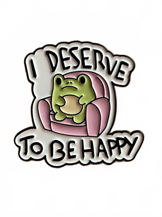 Enamel pin with a frog sitting on a pink sofa and text 'I DESERVE TO BE HAPPY' on a white background