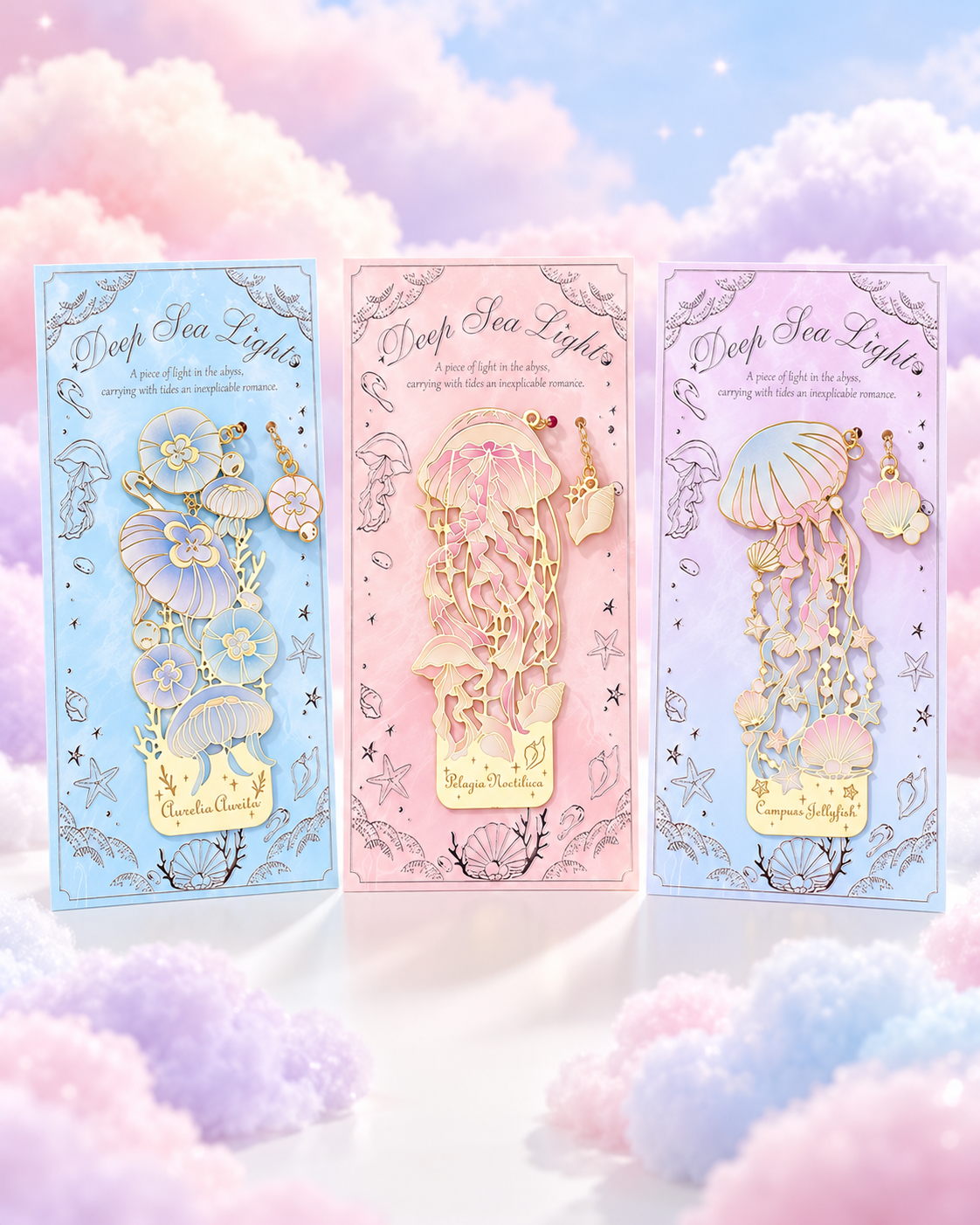 Three packaged gold-tone metal bookmarks with pastel jellyfish and ocean designs on pastel clouds.