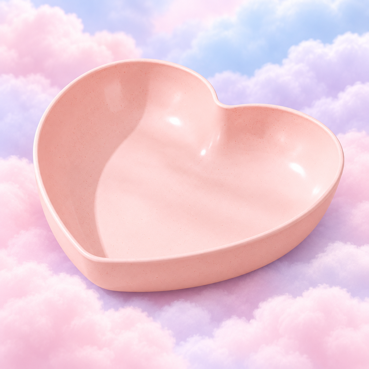 Pink heart-shaped plastic bowl with a speckled finish on pastel clouds.