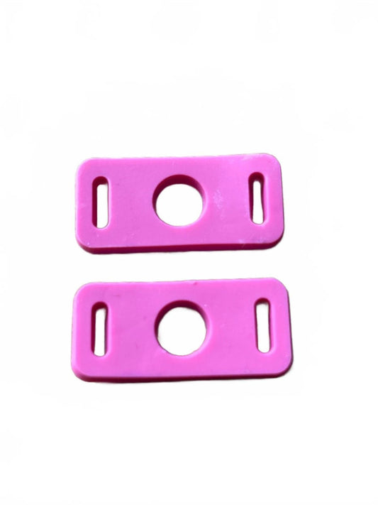 Two pink plastic clips aka shoe charm adaptors on a white background
